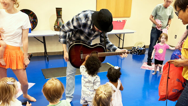 音楽クラスでミュージシャンのギターを順番に触らせてもらう子どもたち