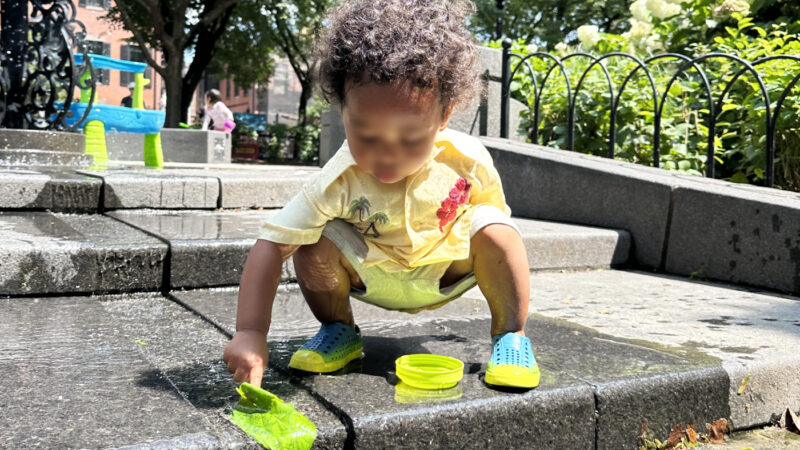 浅い溝を流れる水で遊ぶ子ども。水が溜まりにくい構造になっている